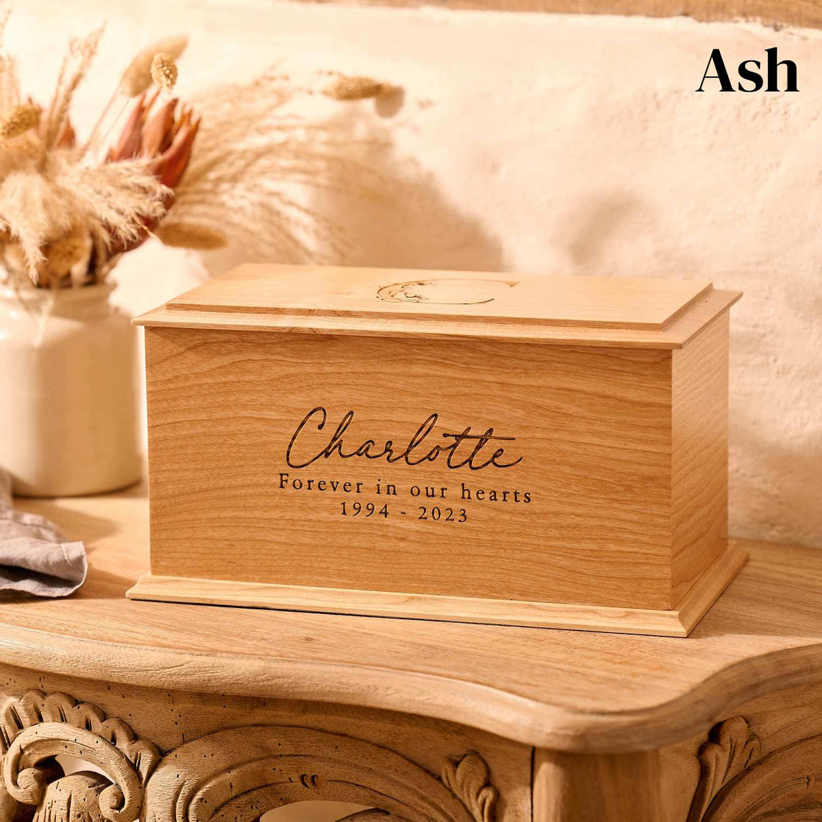 Floral cremation urn crafted from ash wood with personalised engraving.