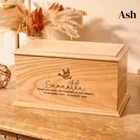 A wooden cremation urn for ashes. The cremation urn is rectangular and is made of ash. It has an engraving showing the outline of a dove in flight, carrying an olive branch in its beak. A personalised engraving underneath the dove reads "Samantha - Gone too soon, yet forever in our hearts. 20 October 2002 - 17 August 2023"