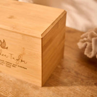 A close up of detail on a personalised cremation urn. The urn is rectangular and is made of a light wood. The photograph is focused on beveling detail around the top face of the urn.