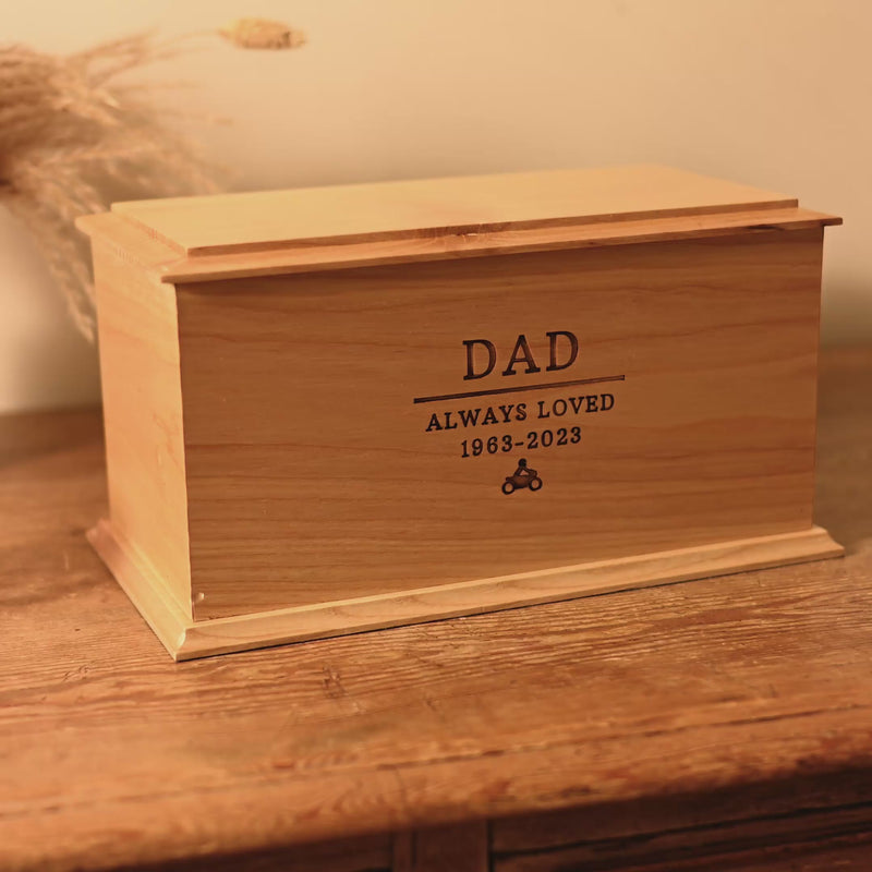 Overview video of personalised wooden cremation urn for human ashes A video showing a wooden cremation urn for ashes from different angles. The urn is made of light wood. It has beveled edges around the lid and bottom face. It is engraved with the words "Dad - Always Loved 1963 - 2023" and a small picture of a person sitting on a motorbike.