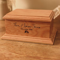 Video shows a small cremation urn for a stillborn baby. The name Thea Eloise Jones is engraved upon it, with a date of birth and a rainbow motif.