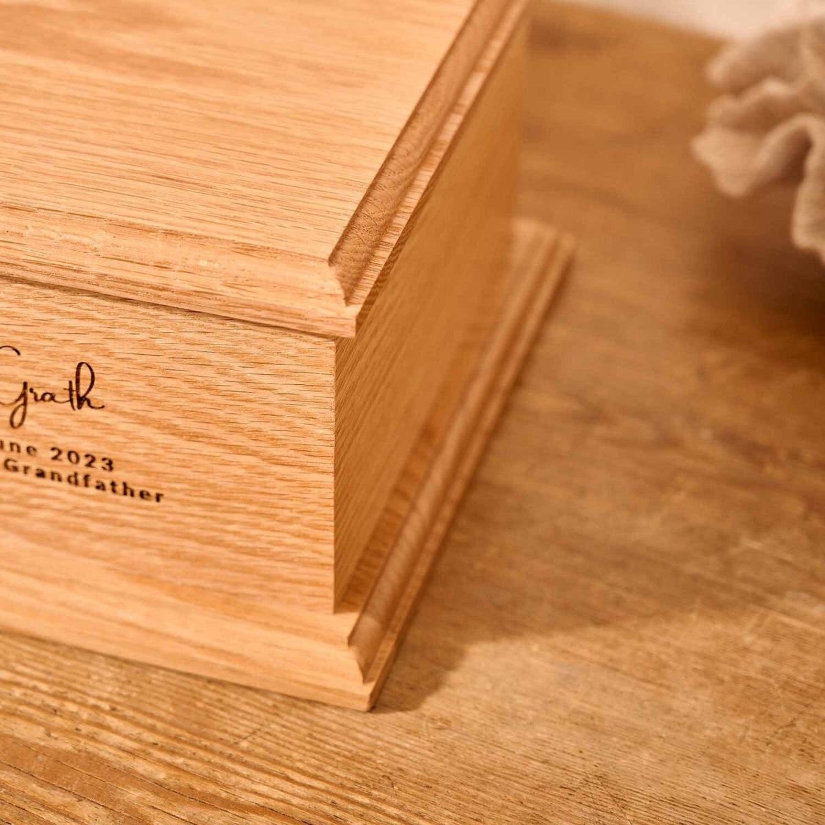 A close up of detail on a personalised cremation urn. The urn is rectangluar and is made of a light wood. The photograph is focused on bevelling detail around the corners and edges of the urn.