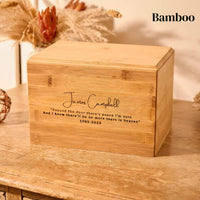 A wooden cremation urn. The urn is rectangular and is made of bamboo. It has a personalised engraving which has a name, a quote and dates of birth and death. The engraving reads "James Campbell - beyond the door there's peace I'm sure, and I know there'll be no more tears in heaven - 1985 -2023"