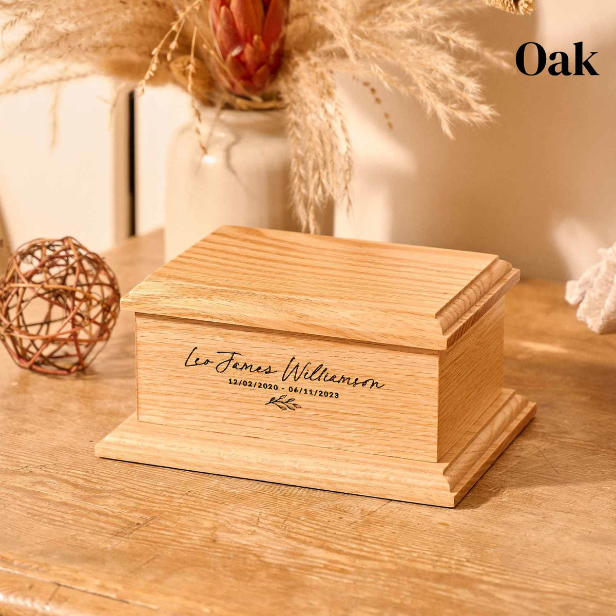 A childrens urn made of oak. It is a personalised urn for ashes. It sits on a table.