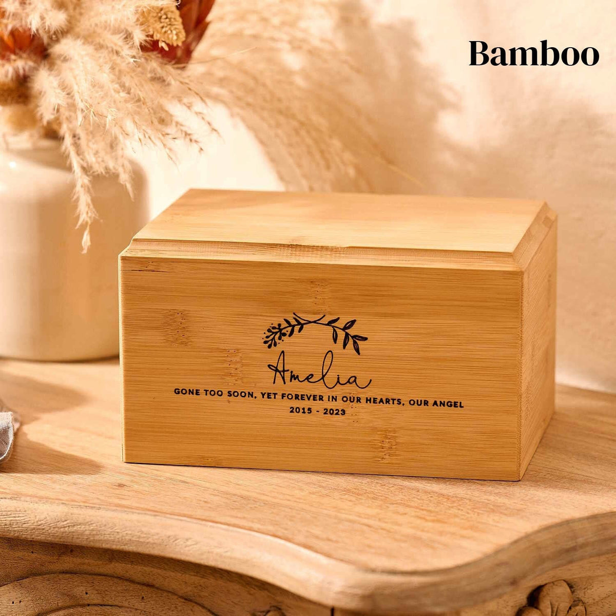 A bamboo urn for a girl sits on a table. The name Amelia is engraved on the child's urn.