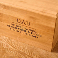 Dad's ashes sit in a wooden urn on a table. The cremation urn says "dad" on the front. This is an urn for cremation ashes.