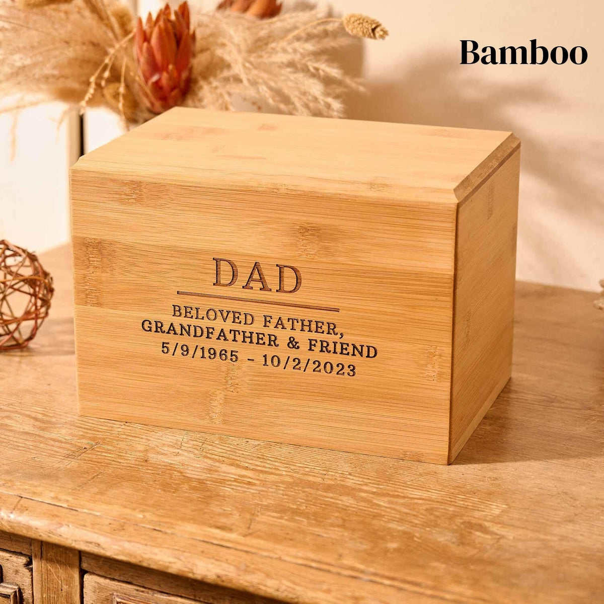 Dad's ashes sit in a wooden urn on a table. The cremation urn says "dad" on the front. This is a bamboo urn for cremation ashes.