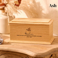 A bespoke urn for a child, made of ash wood sits on a table. It has a dove design.