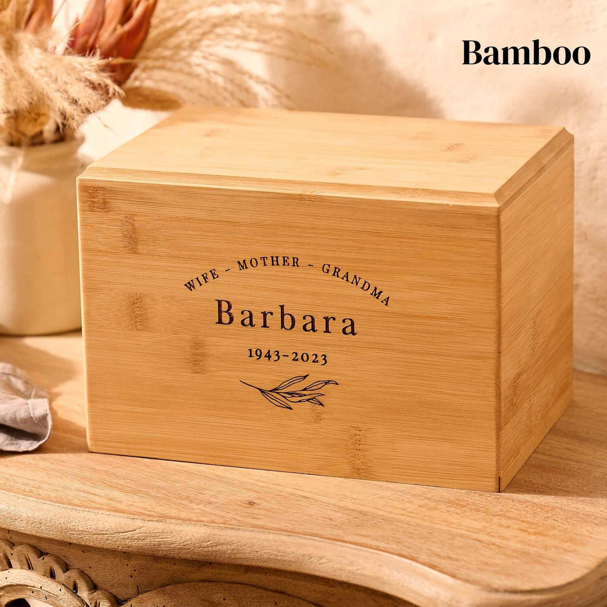 A bamboo cremation urn for an elderly woman sits on a table. Her name, Barbara, is engraved.