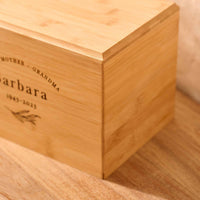 A close up of detail on a personalised cremation urn for ashes. The urn is rectangluar and is made of a light wood. The photograph is focused on bevelling detail around the top face of the urn.