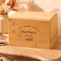 Cremation urn for grandmas ashes sits on a wooden table. It is personalised and has the name Barbara on it. 